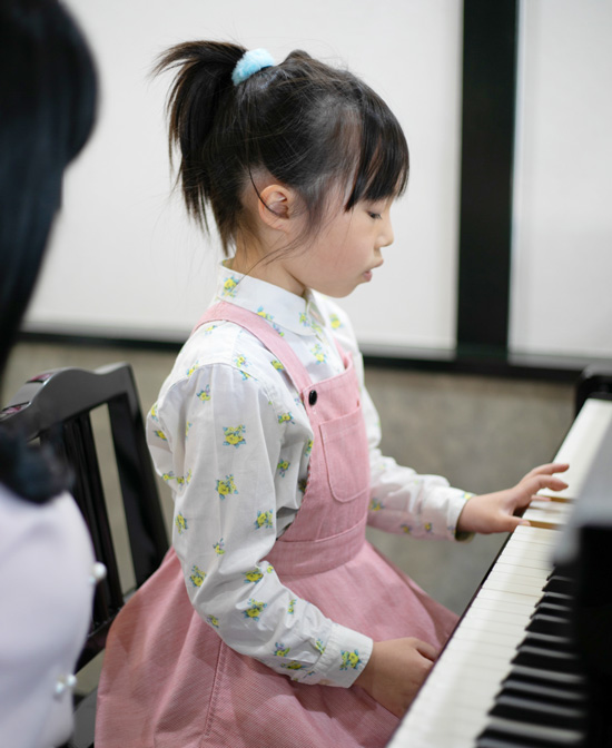 ピアノを弾くピンクの洋服の女の子の写真