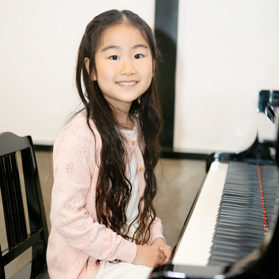 ピアノの前に座る女の子の写真